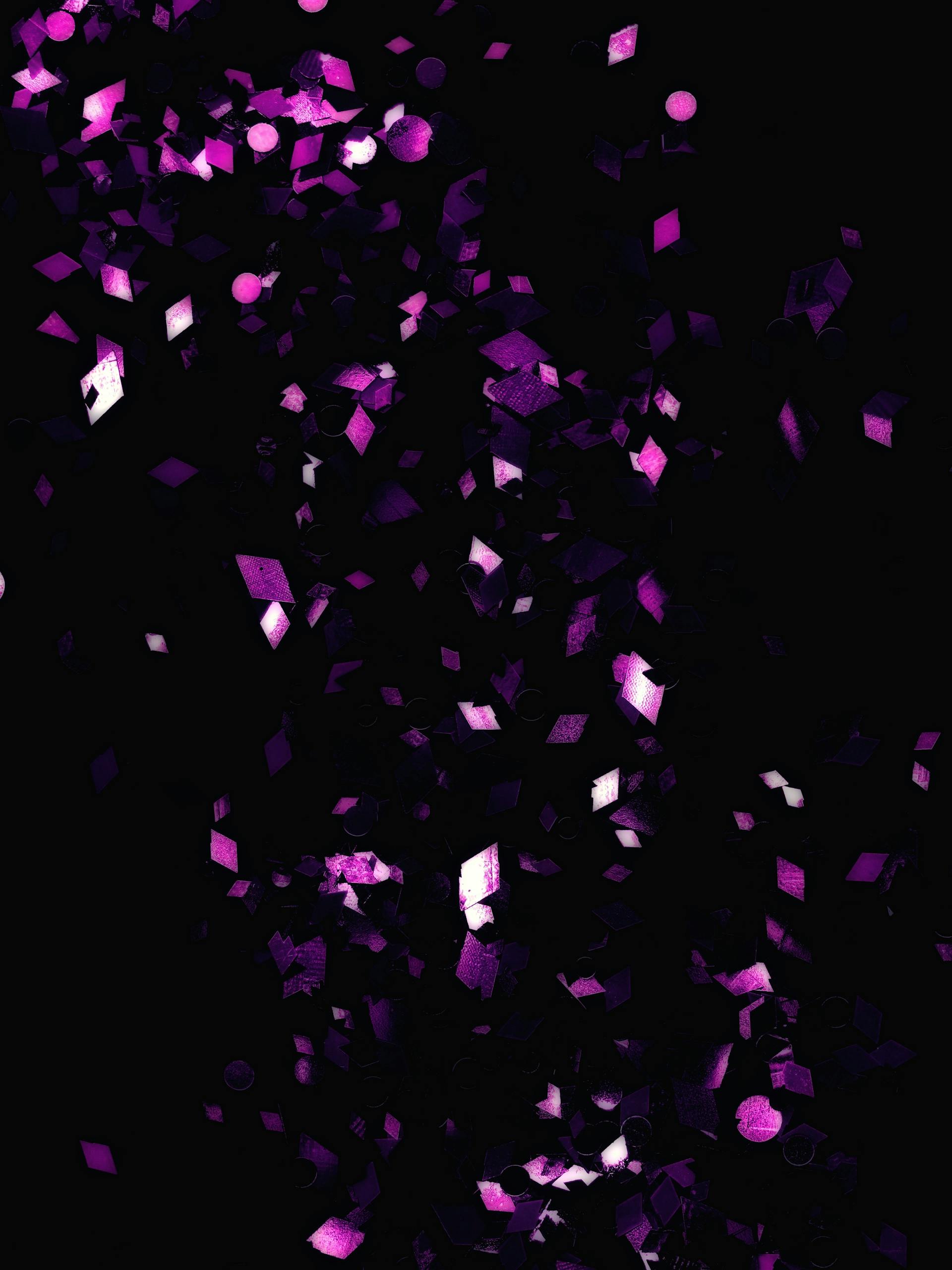 Dynamic purple confetti scattered on a dark black background offers a festive and modern feel.
